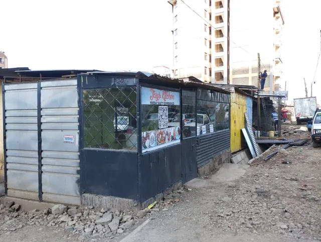 Jays Kitchen seen from the street, between neighbouring shops, with an apartment block behind